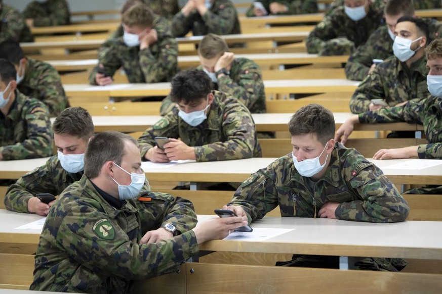 Soldiers of the Swiss army wearing protective face mask looking at their smartphone during a test, with 100 soldiers, of a smart phone app using Decentralized Privacy-Preserving Proximity Tracing (DP- ...