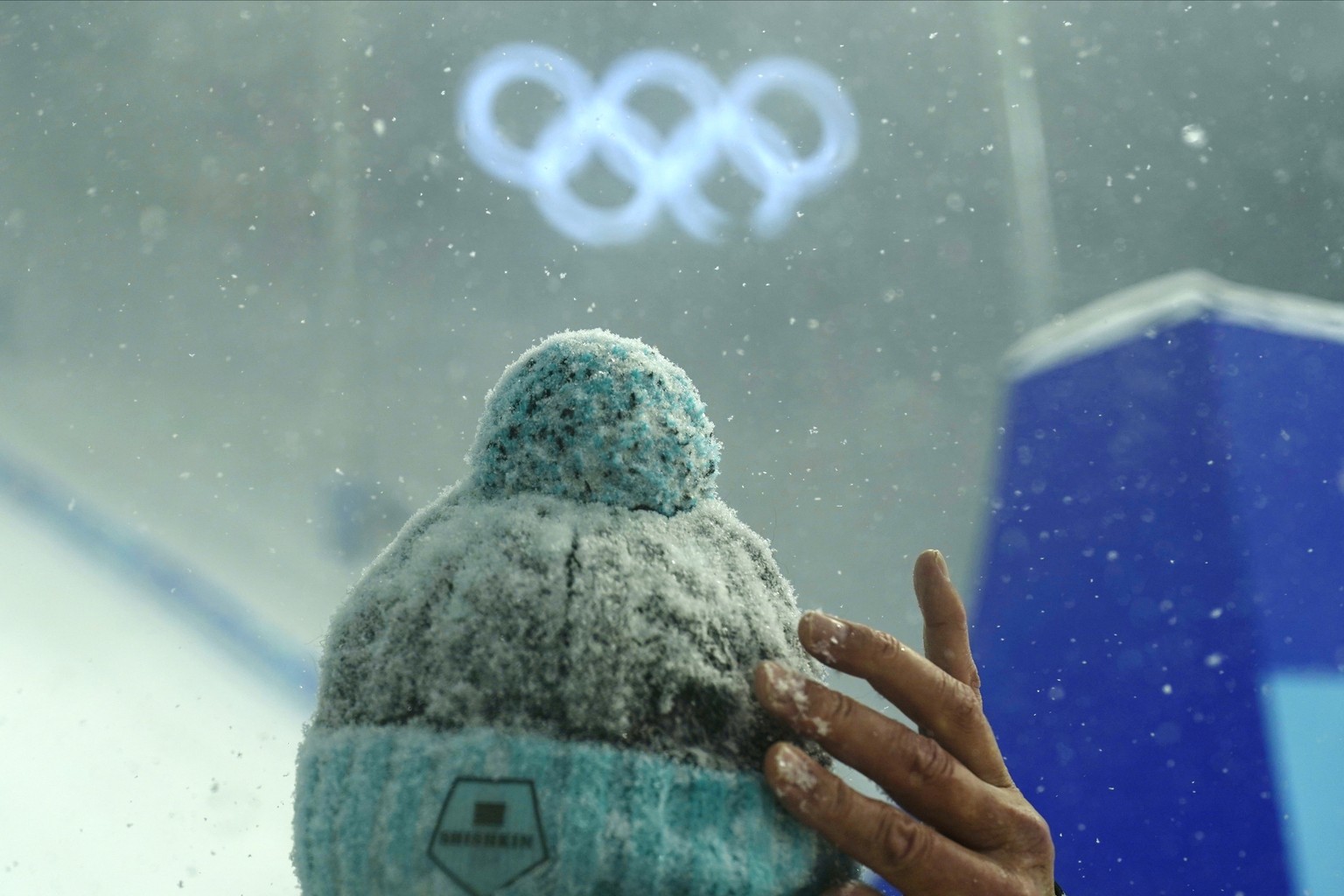 A coach from Kazakhstan waits out in the snow before the women's aerials qualification at the 2022 Winter Olympics, Sunday, Feb. 13, 2022, in Zhangjiakou, China. (AP Photo/Gregory Bull)