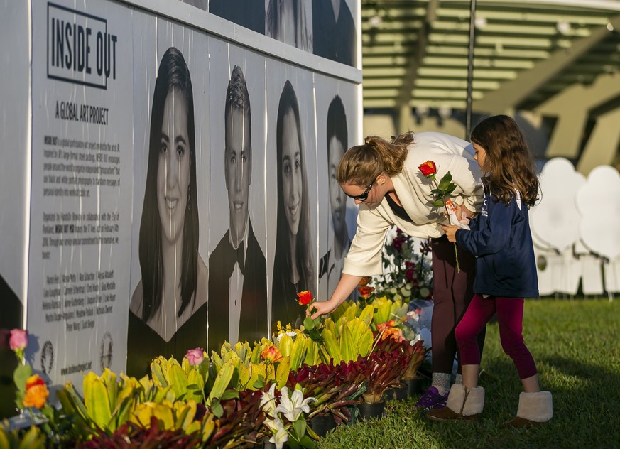 Megan Schuldt and her daughter, Milan, 5, place flowers near a memory wall during a community commemoration event for the Marjory Stoneman Douglas High School victims at Pine Trails Park in Parkland,  ...