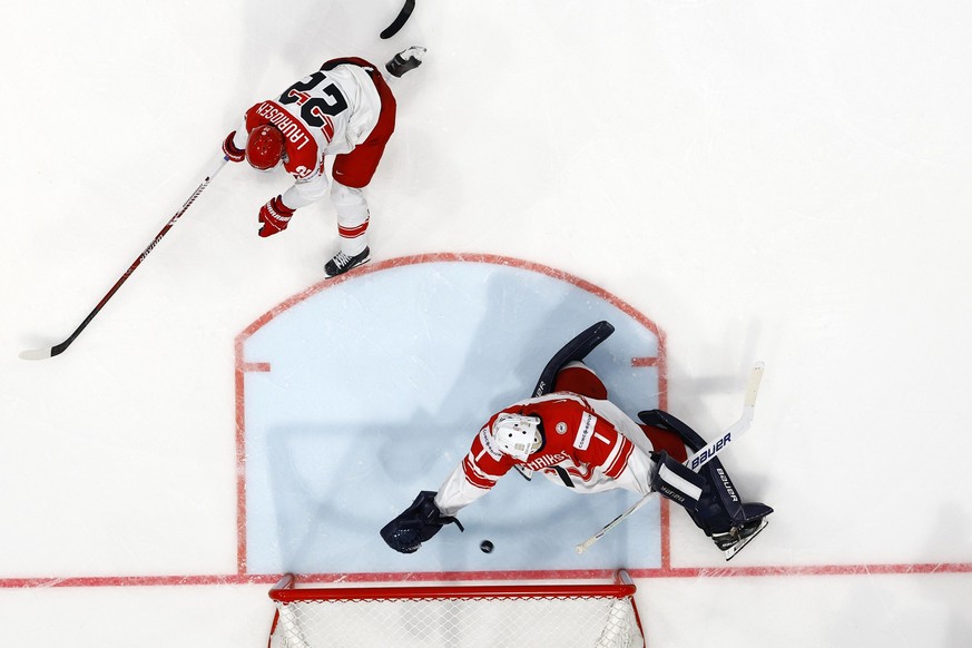 Denmark's Markus Lauridsen, left, and Denmark's goaltender Nicolaj Henriksen, right, concedes a goal during the 2026 IIHF Men's Ice Hockey World Championship preliminary round group B g ...