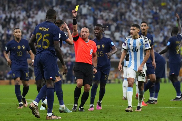 Referee Szymon Marciniak, of Poland, books France&#039;s Marcus Thuram during the World Cup final soccer match between Argentina and France at the Lusail Stadium in Lusail, Qatar, Sunday, Dec. 18, 202 ...