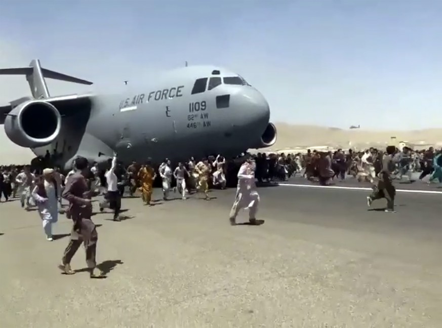 Hundreds of people run alongside a U.S. Air Force C-17 transport plane as it moves down a runway of the international airport, in Kabul, Afghanistan, Monday, Aug.16. 2021. Thousands of Afghans have ru ...