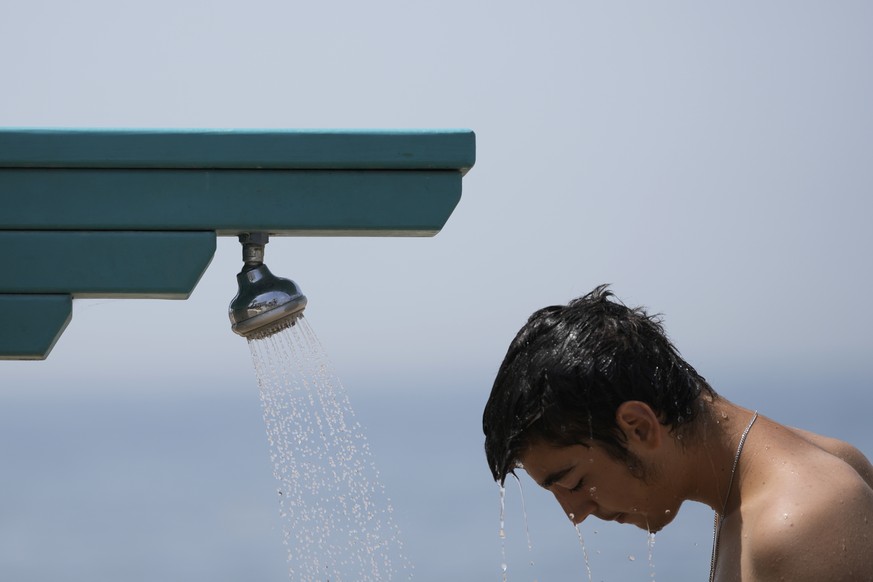 A man stands under a shower at the public beach of Paleo Faliro, in southern Athens, Greece, on Thursday, June 23, 2022. Temperatures reached 40°C (104°F) in parts of southern Greece Friday as a June ...