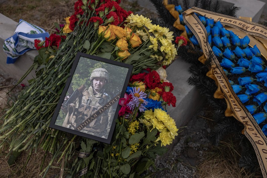 epa10029966 A photo of the Ukrainian serviceman Oleksandr Adamovych, who was killed fighting near Toretsk town in the Donetsk region, lays on flowers during the funeral ceremony, at a cemetery in Boya ...