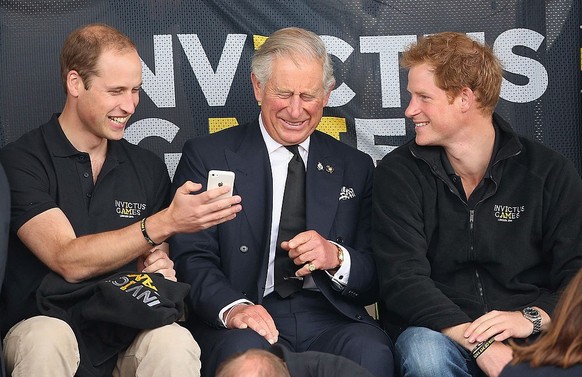 LONDON, ENGLAND - SEPTEMBER 11: Prince William, Duke of Cambridge, Prince Harry and Prince Charles, Prince of Wales look at a mobile phone as they watch the athletics at Lee Valley Track during the In ...