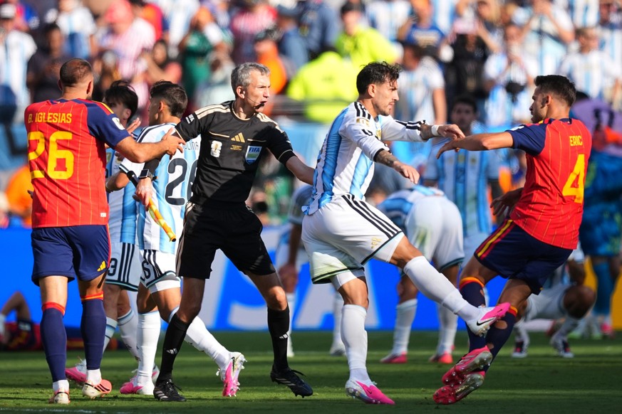 FILE - Argentina's Leandro Paredes (5) kicks at Spain's Eric Garcia (4) as assistant referee Tomaz Klancnik, of Slovenia, tries to break up a scuffle after the World Cup final soccer match b ...