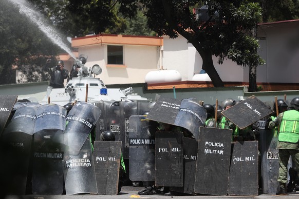 epa10202599 Military police spray a water canon and take cover from projectiles launched by demonstrators during a protest for the 43 disappeared students of Ayotzinapa, in Mexico City, Mexico, 23 Sep ...