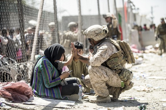 In this image provided by the U.S. Marine Corps, a Marine with Special Purpose Marine Air-Ground Task Force-Crisis Response-Central Command gives a high five to a child at Hamid Karzai International A ...
