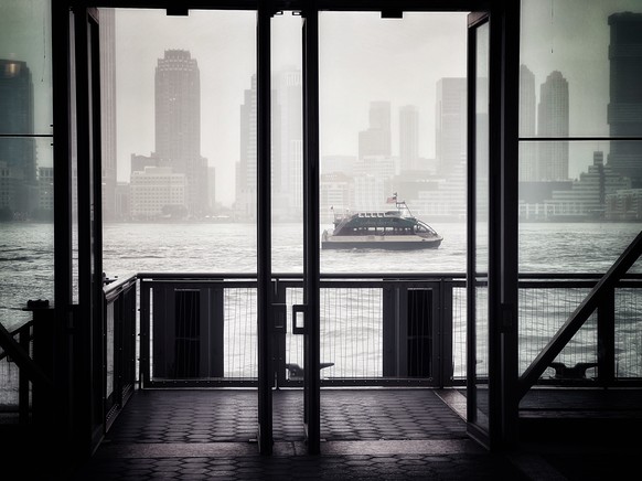 A ferry boat is framed in the doors of a passenger ferry pier, as it motors up the Hudson River on a foggy afternoon in the New York City area in this Wednesday, June 22, 2022 photo taken with an iPho ...
