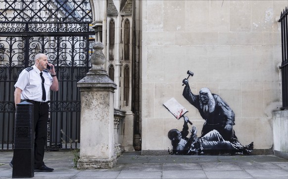 Undated photo released by Banksy of the new artwork by the artist which portrays a judge beating a protester with a gavel at the Royal Courts of Justice in London. (Banksy via AP)
Britain Banksy