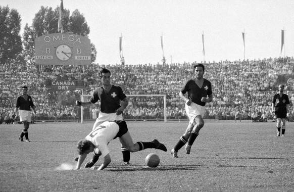 Ein oesterreichischer Spieler stuerzt bei einem Kampf um den Ball mit den Schweizer Spielern Willy Kernen, Mitte, und Roger Boquet, rechts, links hinten, Roger Vonlanthen, aufgenommen am 26. Juni 1954 ...