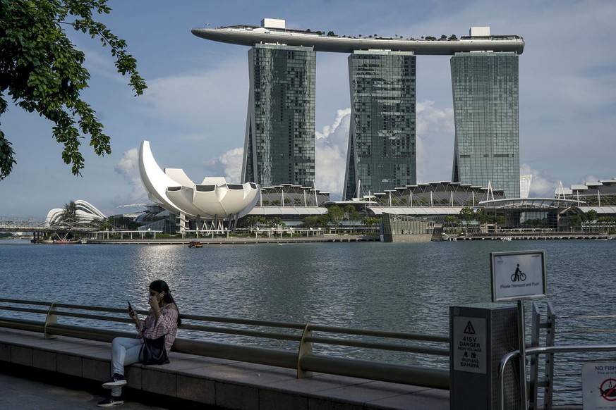 epa09134679 A woman sits along a ledge pictured against Marina Bay Sands Hotel in Singapore, 14 April 2021. The Ministry of Trade and Industry reported that the Singapore economy grew 0.2 percent for  ...