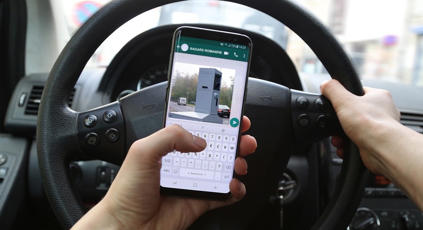 KORTRIJK, BELGIUM -JANUARY 30ST 2018: Person texting and driving on a Samsung Galaxy S8 phone. The left hand typed a message on the WhatsApp app. Concept of dangerous behavior. Illustrative editorial.