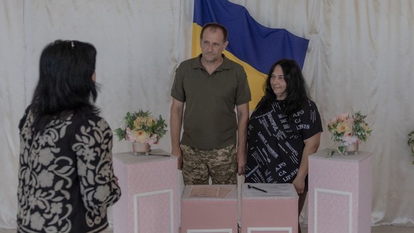 Ukrainian serviceman Volodymyr (C) and Iryna (R) attend their wedding ceremony as an air raid siren soundsin the town of Izium, in the eastern Kharkiv region on July 29, 2026, amid the Russian invasio ...