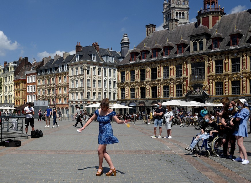 FILE - In this June 6, 2021 file photo, a woman dances by a cafe terrace in Lille, northern France. France is lifting mandatory mask-wearing outdoors and will halt an eight-month nightly coronavirus c ...