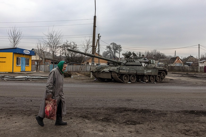 epaselect epa09861036 An elderly woman walks past a damaged Russian tank in recaptured by the Ukrainian army Trostyanets town, in Sumy region, Ukraine, 30 March 2022. Trostyanets was recaptured by the ...