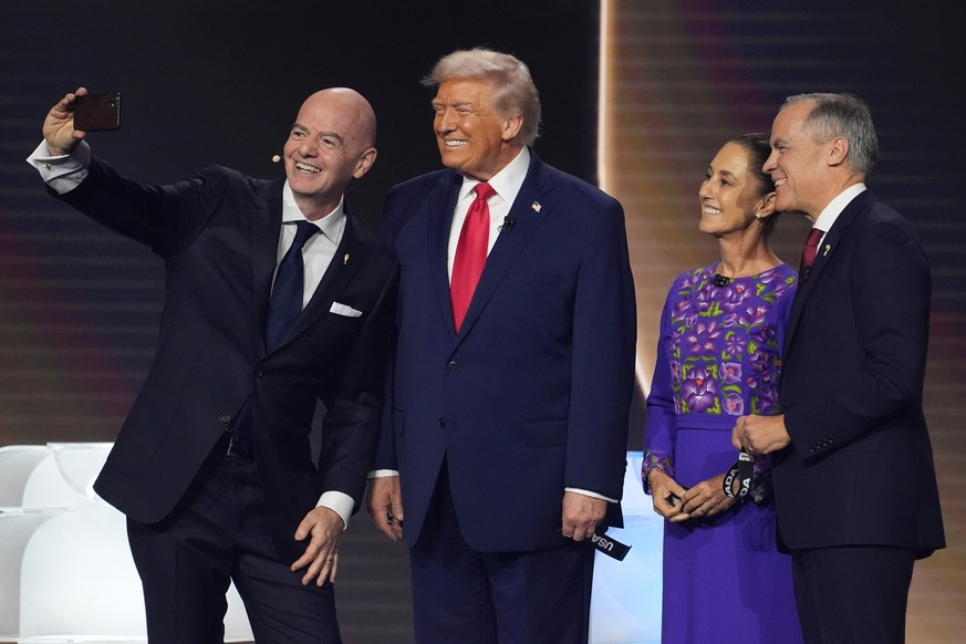 From l-r., FIFA President Gianni Infantino takes a selfie with President Donald Trump, Mexican President Claudia Sheinbaum, and Canadian Prime Minister Mark Carney during the draw for the 2026 soccer  ...