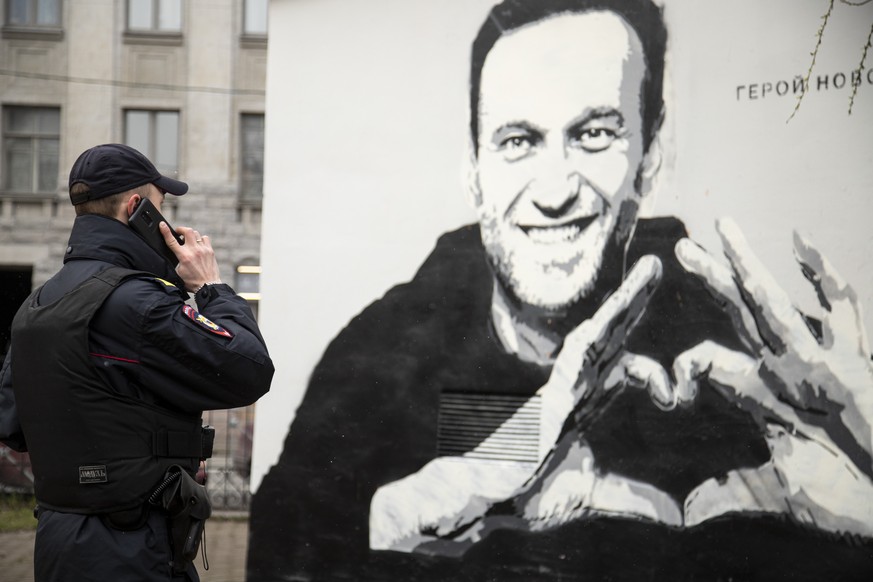 A police officer speaks on the phone near to graffiti of Russia&#039;s imprisoned opposition leader Alexei Navalny in St. Petersburg, Russia, Wednesday, April 28, 2021. (AP Photo/Ivan Petrov)