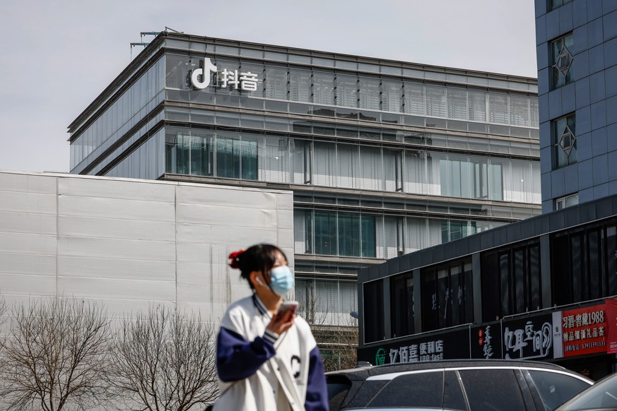 epa10525604 A woman walks along a ByteDance building with the Douyin logo, the Chinese counterpart of TikTok in Beijing, China, 16 March 2023. The Biden administration has threatened to ban TikTok in  ...