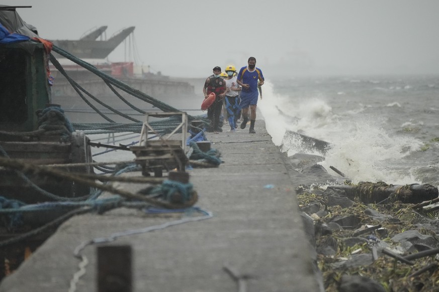 Rescuers run as they check residents living at the seaside slum district of Tondo while Typhoon Noru approaches Manila, Philippines, Sunday, Sept. 25, 2022. The powerful typhoon shifted and abruptly g ...