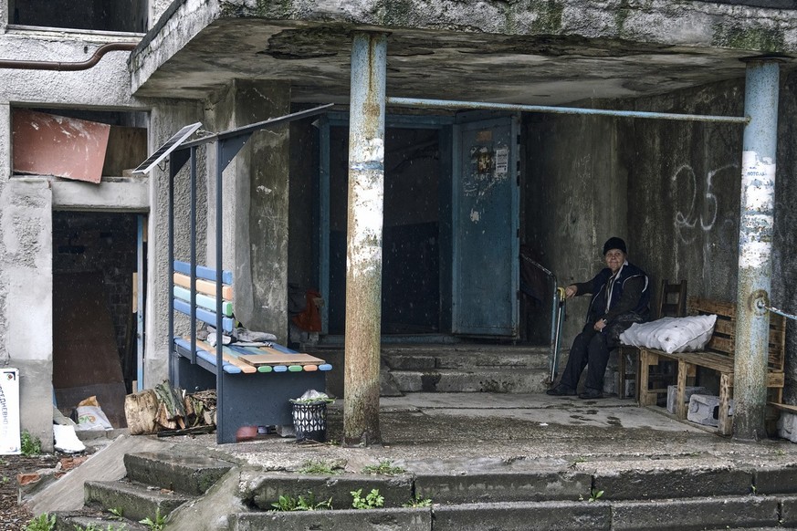 A woman sits in front of a building in Avdiivka, the site of heavy battles with Russian troops in the Donetsk region, Ukraine, Tuesday, April 25, 2023. (AP Photo/Libkos)