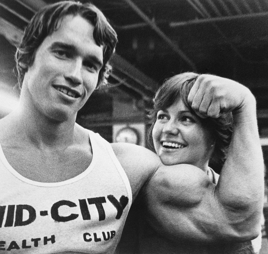 (Original Caption) NEW YORK: Arnold (Mr. Universe) Schwarzenegger supplies a chinrest for Sally (The Flying Nun) Field as they take a break from a bodybuilding workout session here 4/20. They began th ...