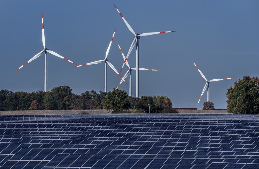 FILE - Wind turbines turn behind a solar farm in Rapshagen, Germany, Thursday, Oct. 28, 2021. Proponents of clean energy and thinks tanks have long said it&#039;s possible to reduce emissions and keep ...