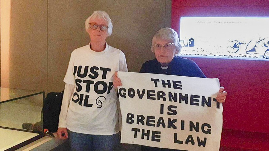 In this photo provided by Just Stop Oil on Friday, May 10, 2024, two activists Judy Bruce, a retired biology teacher and Reverend Sue Parfitt, hold up a sign, after they targeted the protective enclos ...