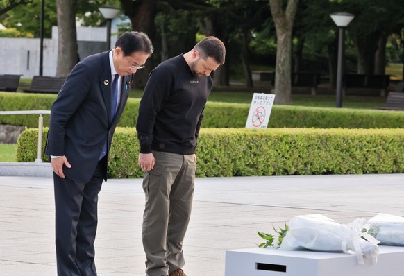 epa10643212 A handout photo made available by the G7 Hiroshima Summit Host shows Japan?s Prime Minister Fumio Kishida (L) and Ukraine&#039;s President Volodymyr Zelensky bow after laying flowers in fr ...