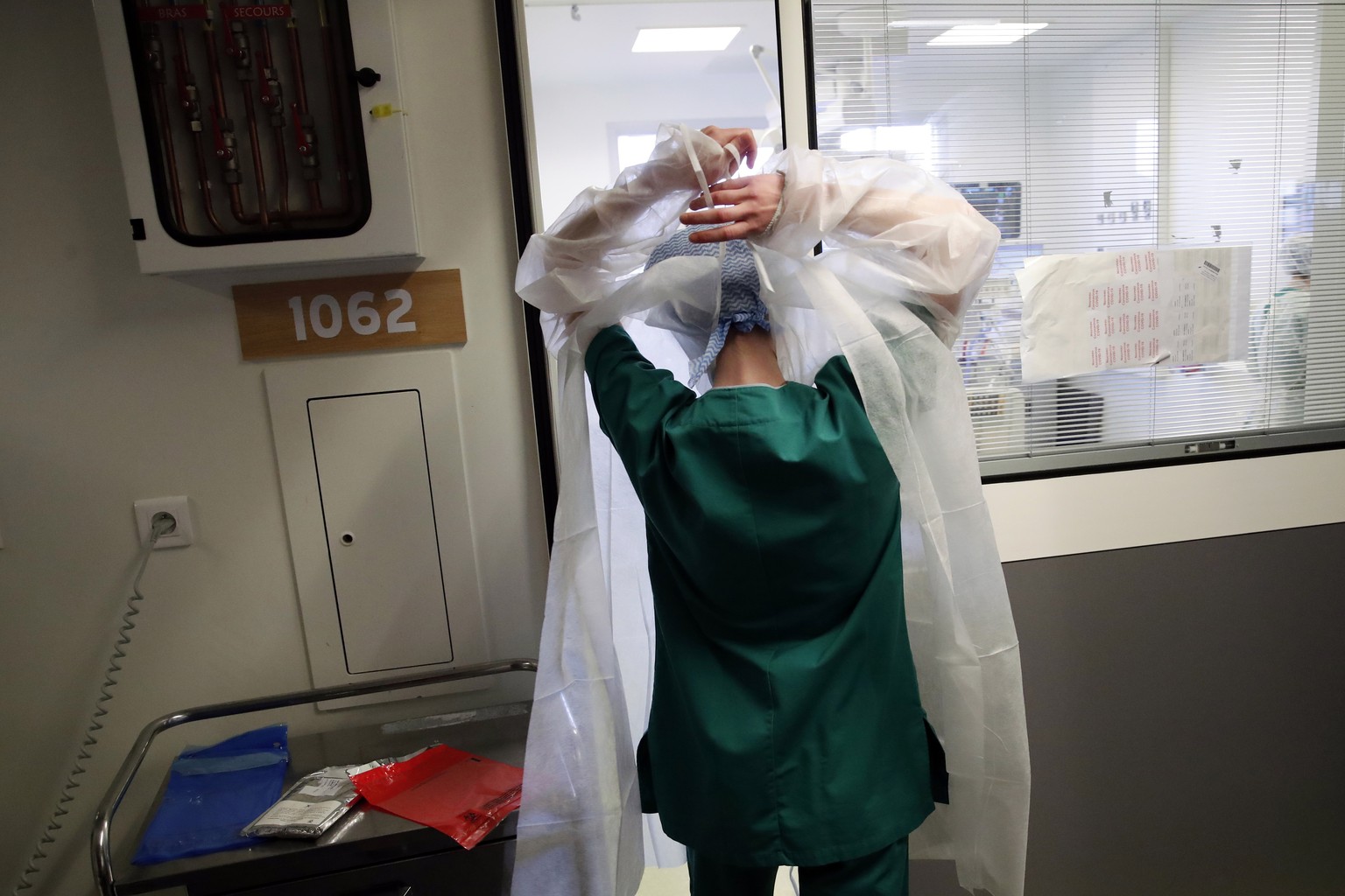 A medical worker prepares to tend to a patient affected with the COVID-19 in the Amiens Picardie hospital Tuesday, March 30, 2021 in Amiens, 160 km (100 miles) north of Paris. France is now facing a d ...