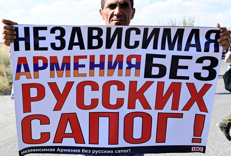 An Armenian protester holds a placard reading, &quot;An independent Armenia without Russian boots&quot;, as he takes part in a rally to protest against the presence of the 102nd Russian military base  ...