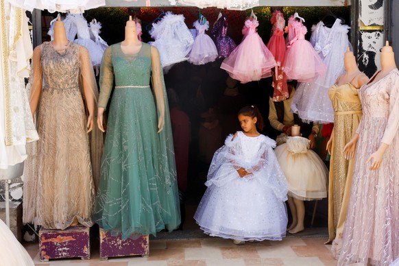 A Palestinian girl tries on a refurbished dress at a shop, as brides in Gaza turn to reused gowns amid soaring prices and shortages caused by the war, in Khan Younis, in the southern Gaza Strip, May 9 ...