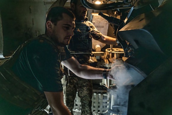 14 juin 2024, Donbass, Ukraine : Deux soldats ukrainiens de la 33e brigade retirent l&#039;obus usagé d&#039;une pièce d&#039;artillerie M109L sur une position près de Kurakhove, dans le Donbas. Les f ...