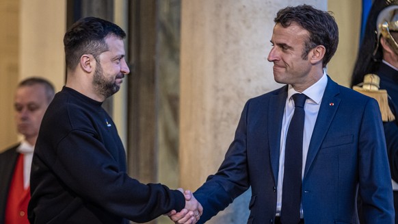 epa10628504 French President Emmanuel Macron (R) shakes hand with his Ukrainian counterpart Volodymyr Zelensky (L), upon his arrival for their meeting at Elysee palace in Paris, France, 14 May 2023. E ...