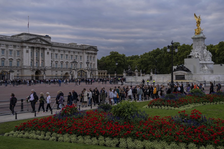 People walk near Buckingham Palace in London, Thursday, Sept. 15, 2022. The Queen will lie in state in Westminster Hall for four full days before her funeral on Monday Sept. 19. (AP Photo/Bernat Arman ...