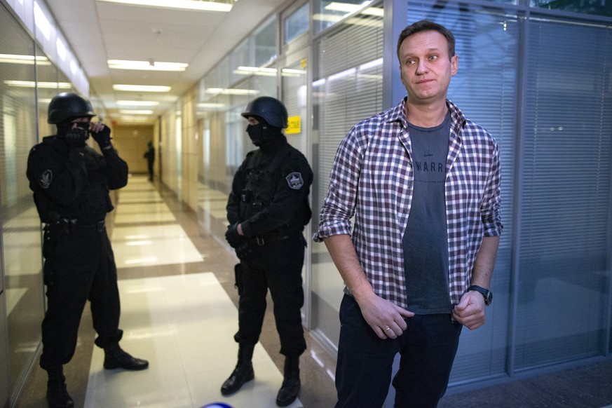 FILE - In this Thursday, Dec. 26, 2019 file, Russian opposition leader Alexei Navalny speaks to the media in front of security officers standing guard at the Foundation for Fighting Corruption office  ...