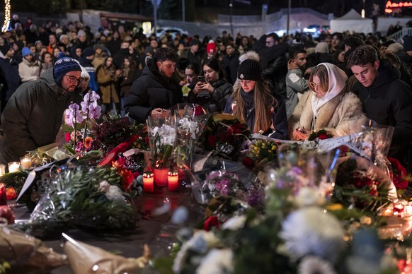 epa12621050 Several hundred mourners gather to lay down flowers and light candles to remember the victims of the fire at the "Le Constellation" bar and lounge, which left people dead and inj ...
