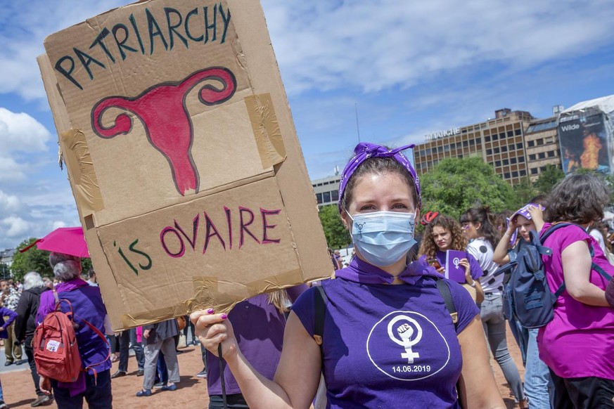 Une femme avec un masque et une pancarte pose sur la Plaine de Plainpalais a Geneve , a l&#039;occasion de la Greve Feministe, ce dimanche 14 juin 2020. La greve feministe du 14 juin se reorganise en  ...