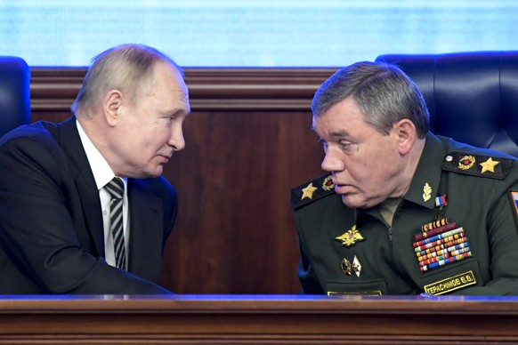 Russian President Vladimir Put, left, and Russian General Staff Valery Gerasimov talk to each other during an extended meeting of the Russian Defense Ministry Board at the National Defense Control Cen ...