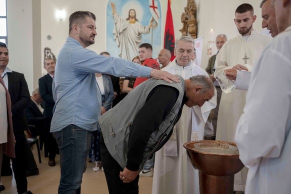 Le père Fran Kolaj (à droite) baptise un homme lors d&#039;une cérémonie à l&#039;église Saint Abraham dans le village de Llapushnik, le 21 avril 2025. Alors que le Vatican vient d&#039;annoncer la mo ...
