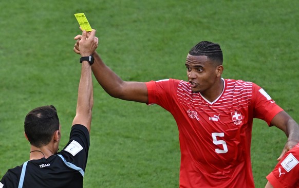 epa10324596 Argentinian referee Facundo Tello shows the yellow card to Manuel Akanji of Switzerland (R) during the FIFA World Cup 2022 group G soccer match between Switzerland and Cameroon at Al Janou ...