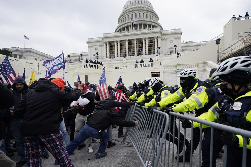 Des insurgés fidèles au président Donald Trump tentent de franchir une barrière de police, au Capitole, à Washington.