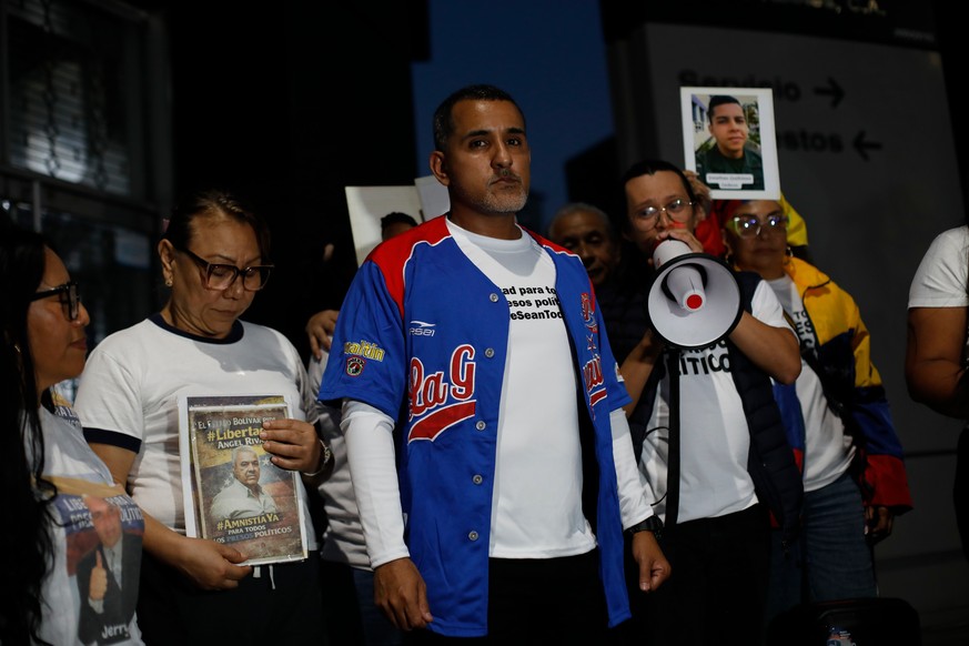 Opposition figure Juan Freites, center, stands with relatives of people they consider political prisoners, after his release from El Helicoide, an intelligence headquarters and detention center, in Ca ...