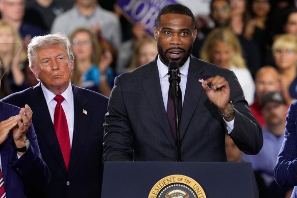 President Donald Trump listens as Republican congressional candidate Amir Hassan speaks at an event at the General Motors Proving Ground Monday, July 27, 2026, in Milford, Mich. (AP Photo/Paul Sancya) ...