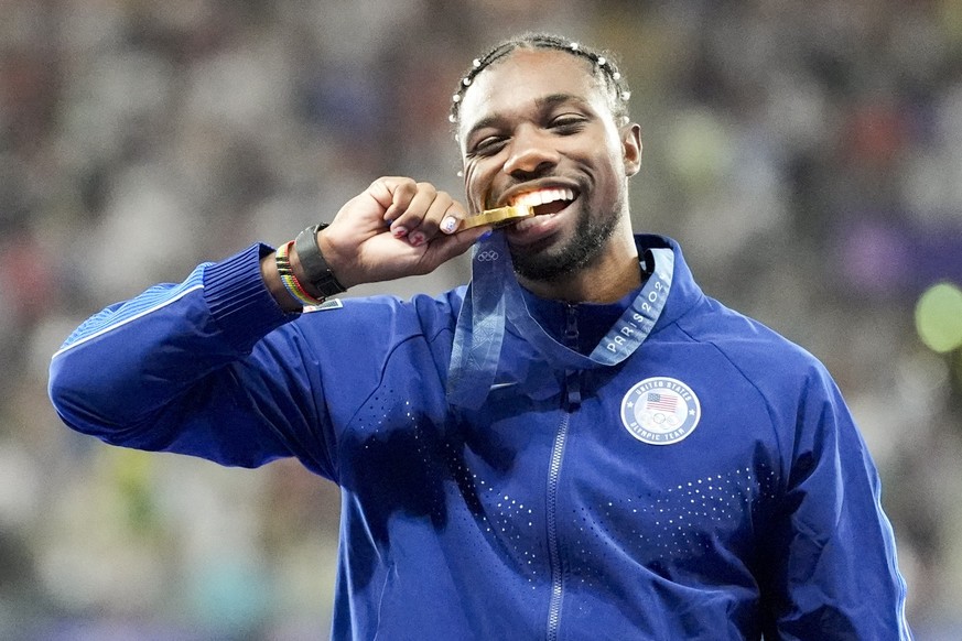 Gold medalist, Noah Lyles, of the United States, poses on the podium after the men's 100-meter final at the 2024 Summer Olympics, Monday, Aug. 5, 2024, in Saint-Denis, France. (AP Photo/Matthias  ...