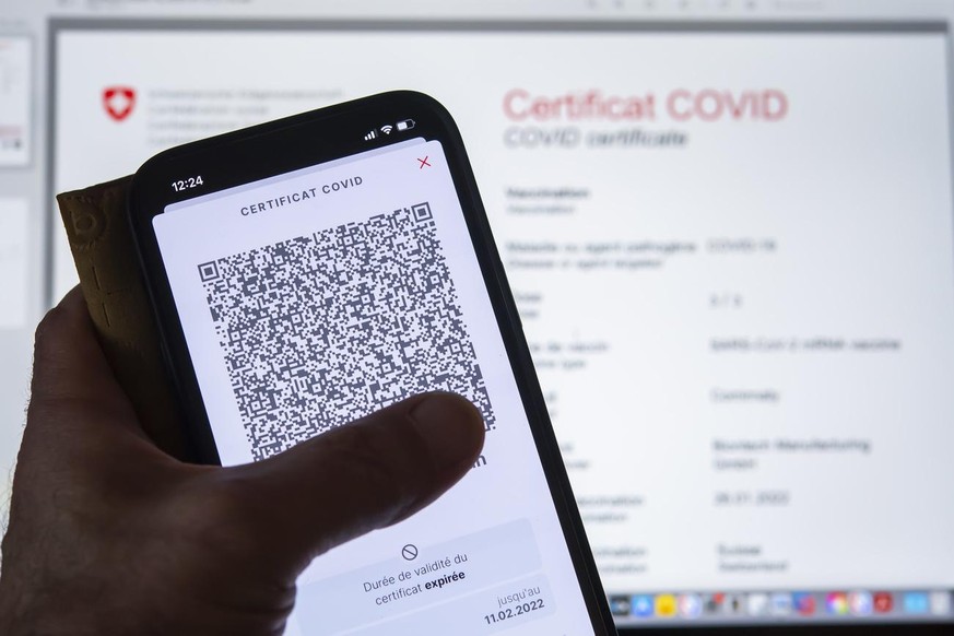 Une personne tient dans sa main un smartphone avec l&#039;application Certificat Covid suisse et son code QR ou il est inscrit &quot;Duree de validite du certificat expiree. Ce certificat ne repond pa ...