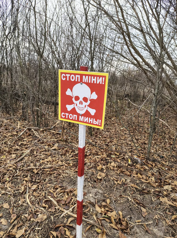 Panneau signalant en ukrainien et en russe la présence d’une mine.