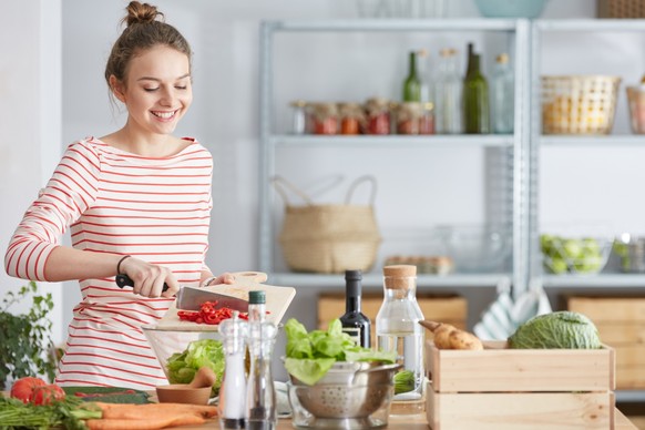 Attractive young woman preparing vegetarian meal in her kitchen