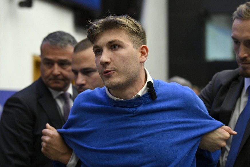 Security officers lead away a man, who disrupted the press conference of Hungarian Prime Minister Viktor Orban ahead of a plenary session at the European Parliament in Strasbourg, France, Tuesday, Oct ...