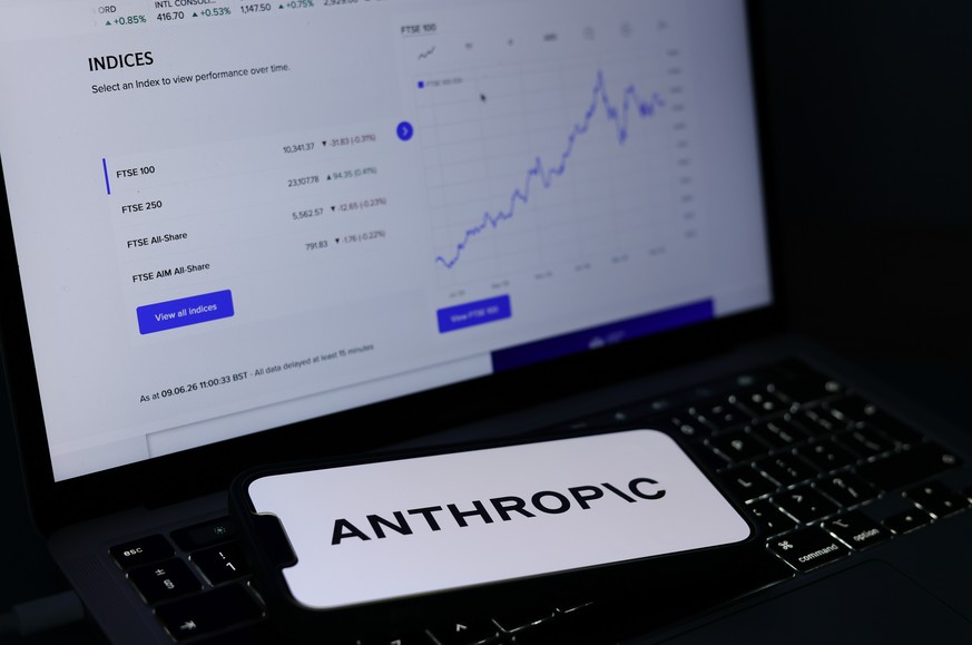 epa13026216 The Anthropic logo is displayed on a mobile phone alongside a stock market graph displayed on a laptop screen in Liverpool, Britain, 09 June 2026. Leading AI (artificial intelligence) and  ...